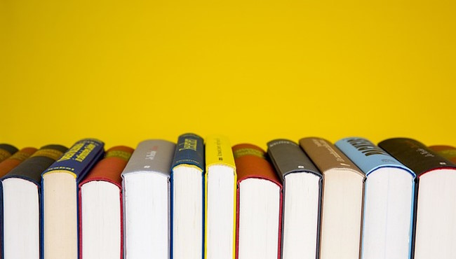 A row of books, spine-up, against a yellow background