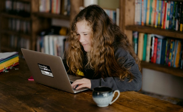 A young woman wearing a school uniform, working on a laptop.